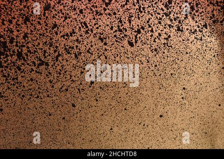 Schwarze und rote Sprühfarbe auf goldfarbenem Papier Stockfoto