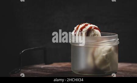 Nahaufnahme von Eisportionierer mit Karamellsauce auf schwarzem Hintergrund Stockfoto