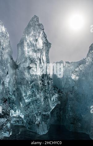 Ein Detailfoto eines kleinen Bereichs eines umgedrehten Eisbergs mit klarem und schwarzem Eis und Hintergrundbeleuchtung in Paradise Bay, Antarktis Stockfoto