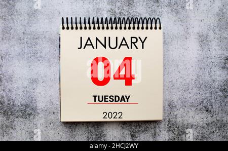 Januar 4 auf weißem Notizpad.Neben ihm ist eine blaue Uhr auf rotem Hintergrund.Kalender für Januar Stockfoto