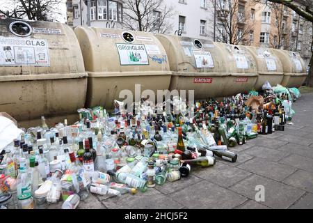 Überlaufene Glasflaschen-Recycling-Behälter mit Reihen von Flaschen, die sich vorne am Fußweg aufgereiht haben, München, Deutschland, Europa. Stockfoto