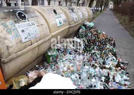 Überlaufene Glasflaschen-Recycling-Behälter mit Reihen von Flaschen, die sich vorne am Fußweg aufgereiht haben, München, Deutschland, Europa. Stockfoto