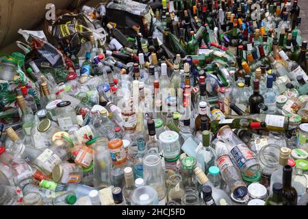 Nahaufnahme der Reihen von Flaschen, die vor den Recycling-Glasflaschenbehältern aufgereiht sind, München, Deutschland, Europa. Stockfoto