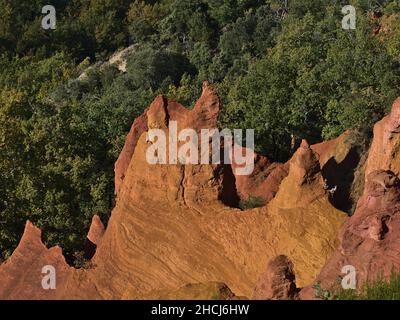 Hochwinkelansicht der beeindruckenden orangefarbenen ockerfarbenen Felsformationen bei Colorado Provenzal im Luberon-Tal bei Rustrel, Provence, Frankreich an sonnigen Tagen. Stockfoto
