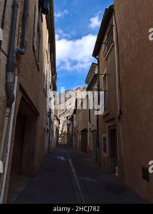 Abnehmende Perspektive der engen Gasse im historischen Zentrum der Stadt Sisteron, Provence, Frankreich mit charakteristischen alten Gebäuden und Berg. Stockfoto