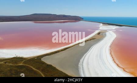 Panorama-Luftaufnahme der hellen Farbe berühmten natürlichen Ort - rosa See auf der Krim mit erstaunlichen Küste und türkisfarbenem Meer auf dem Hintergrund. Einzigartiger pi Stockfoto