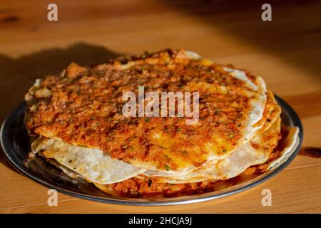 Traditionelle köstliche türkische Küche, Speisen; türkische Pizza oder Lahmacun wird aus Hackfleisch und Zwiebeln auf einem Holztisch hergestellt Stockfoto