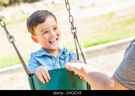 Chinesischer und kaukasischer Junge mit Spaß auf den Schaukeln auf dem Spielplatz. Stockfoto