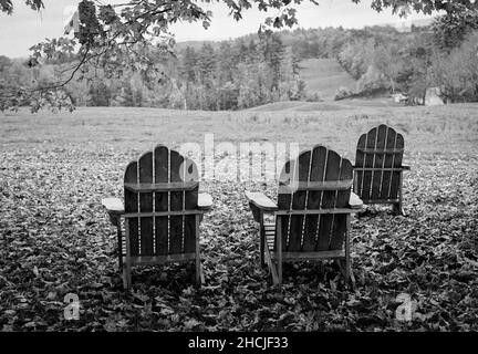 Eine Reihe von Holz Adirondack Stühle in am Rande einer Weide an einem bewölkten Herbsttag. Canterbury Shaker Village, New Hampshire USA. Das Bild war Captu Stockfoto