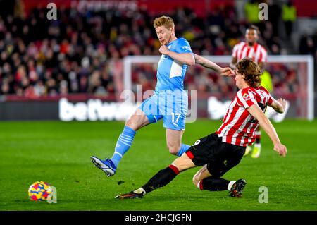 London, Großbritannien. 29th Dez 2021. Kevin De Bruyne vom Manchester City FC fährt beim Premier League-Spiel zwischen Brentford und Manchester City am 29. Dezember 2021 im Brentford Community Stadium, London, England, gegen Mads Bech Sorensen vom Brentford FC. Foto von Phil Hutchinson. Nur zur redaktionellen Verwendung, Lizenz für kommerzielle Nutzung erforderlich. Keine Verwendung bei Wetten, Spielen oder Veröffentlichungen einzelner Clubs/Vereine/Spieler. Kredit: UK Sports Pics Ltd/Alamy Live Nachrichten Stockfoto