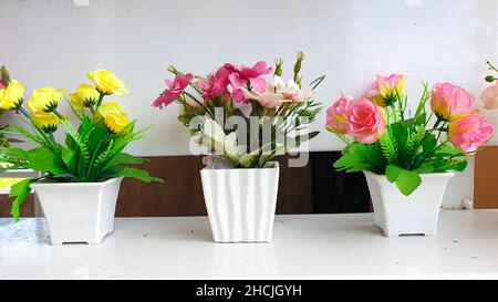 Künstlicher Strauß von Rosen und Lilien in Töpfen, Innen- und Außendekoration. Stockfoto