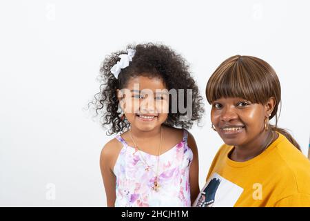 4 oder 5-jähriges Mädchen mit lächelnder Mutter, die vor weißem Hintergrund für ein Porträt posiert Stockfoto