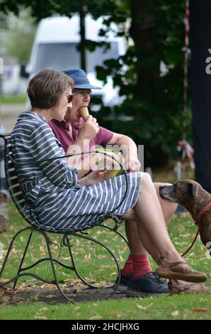 Ehepaar mittleren Alters mit Hund essen Eis und Snacks im Park beccles suffolk england Stockfoto