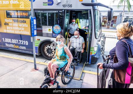 Miami Beach Florida Bushaltestelle Miami-Dade Metrobus Behinderte behinderte Frau Mann Paar Aussteigen Rollstuhl Rollstühle tragen Gesichtsmasken Covi Stockfoto