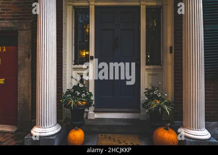 Blick auf eine Wohnung Außentür und Dekoration von Pflanzen und Kürbissen für Thanksgiving. Stoop mit Gebäudesäulen Stockfoto