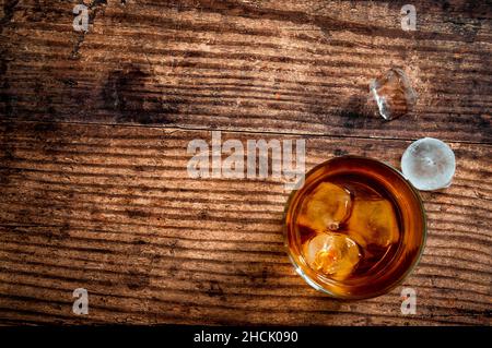 Konzept für alkoholische Getränke und alkoholische Getränke mit einer Ansicht von oben oder über der Tischplatte eines Glases Bourbon-Whiskys auf einem Holztisch Stockfoto