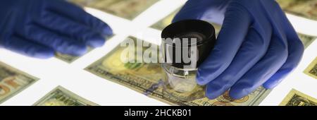 Mann in Gummihandschuhen, der die Echtheit von us-Dollar-Scheinen aus der Nähe bestätigt Stockfoto