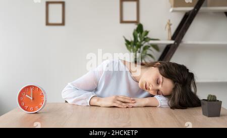 Müde Mädchen Geschäftsmann schlafen am Tisch im Büro. Junge, überarbeitete, abgemagerte Dame arbeitet von zu Hause aus. Ich schlief während der Arbeitszeit ein. Ein Stockfoto