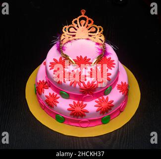 Wunderschönes, hausgemachtes, zweistufiges Hochzeitsparty-Kuchen-Design mit einer Tiara auf der Oberseite, verziert mit Puderblumen. Köstlicher rosarot-roter Rundkuchen mit Thema Stockfoto