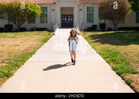 Kinderpuppe mit Rucksäcken im Park in der Nähe der Schule. Schuljunge mit Rucksäcken im Freien. Bildungskonzept für Kinder. Stockfoto