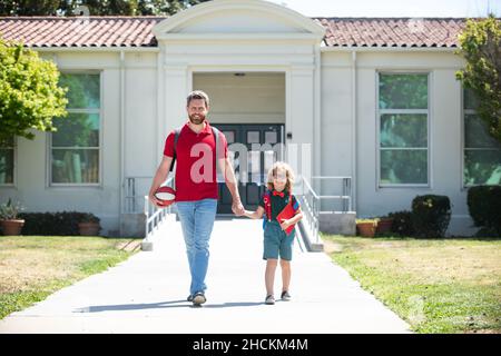 Vater unterstützt und motiviert Sohn. Kind geht zur Grundschule. Stockfoto