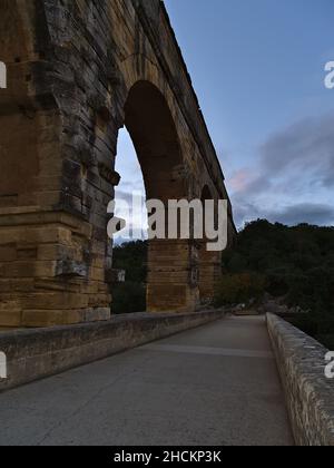Schöne Aussicht auf das antike römische Aquädukt Pont du Gard am Abend in der Nähe von Vers-Pont-du-Gard, Oczitanie, Frankreich mit leerer Brücke und Steinsäulen. Stockfoto