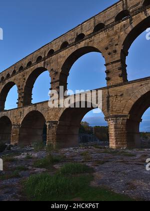 Blick auf das antike römische Aquädukt Pont du Gard mit majestätischen Steinsäulen über dem Fluss Gardon nach Sonnenuntergang in der Nähe von Vers-Pont-du-Gard, Oczitanie, Frankreich. Stockfoto