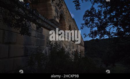 Schöner Blick auf das antike römische Aquädukt Pont du Gard, das im Dunkeln aus großen Steinblöcken in der Nähe von Vers-Pont-du-Gard, Oczitanie, Frankreich, erbaut wurde. Stockfoto