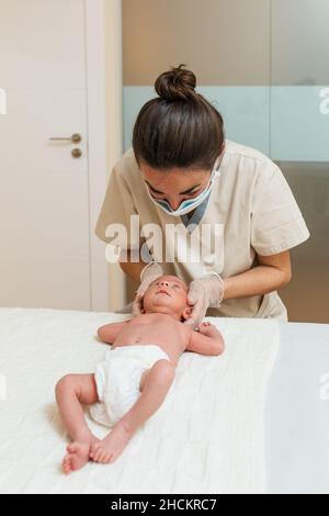 Physiotherapeutin, die eine Plagiokephalie-Korrektur an einem Neugeborenen in einem Therapiezentrum macht. Stockfoto
