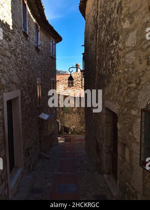 Schöner Blick auf eine schmale, leere Gasse zwischen traditionellen Steinhäusern im historischen Zentrum des kleinen Dorfes Eze an der französischen Riviera. Stockfoto