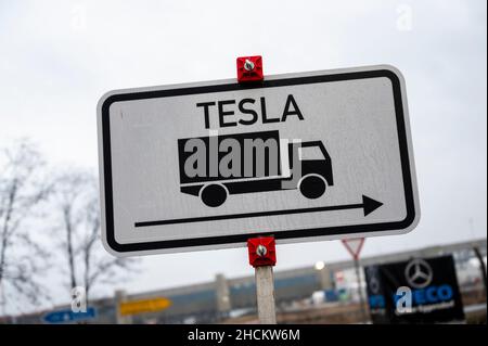 30. Dezember 2021, Brandenburg, Grünheide: An einer Zufahrtsstraße zum zukünftigen Tesla Gigafactory Berlin Brandenburg befindet sich ein Straßenschild mit der Aufschrift "Tesla" und ein LKW. Tesla hat nach Angaben der Landesregierung Brandenburg die fehlenden Unterlagen für das Genehmigungsverfahren eingereicht. Foto: Christophe Gateau/dpa Stockfoto