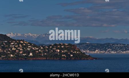 Atemberaubender Panoramablick auf die felsige mittelmeerküste vom Cap Roux in der Nähe von Saint-Raphael, Französische Riviera, Frankreich mit schneebedeckten Bergen. Stockfoto