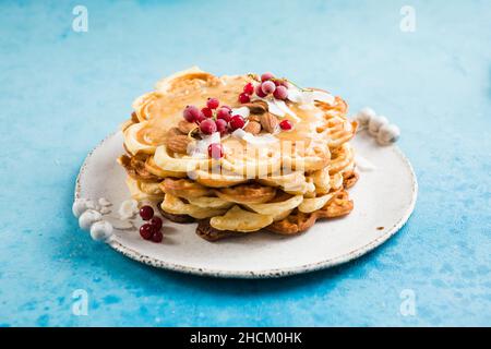 Frisch gebackene hausgemachte herzförmige belgische Waffeln auf blauem Hintergrund. Europäische Backwaren Süßigkeiten. Frühstückskonzept am Valentinstag. Stockfoto