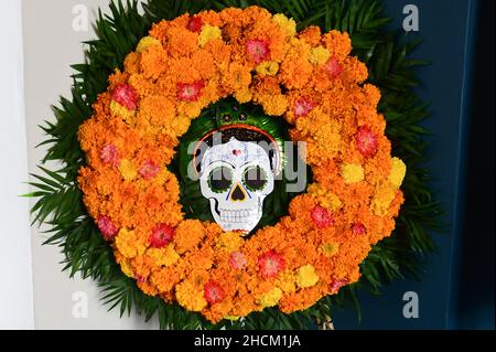Oaxaca De Juarez, Mexiko. 30th Oktober 2021. Ein Kranz aus Studentenblumen, auch Ringelblumen genannt, hängt an einer Tür mit stilisiertem Schädel. Quelle: Sebastian Kahnert/dpa-Zentralbild/dpa/Alamy Live News Stockfoto