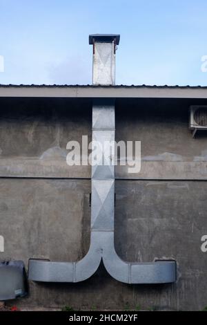 Glänzender Metallkamin an der Außenwand. Aus Zink für die Luftzufuhr in der Restaurantküche Stockfoto