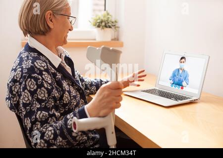 Ältere Patientin mit Mobilitätsproblem spricht über Internet-Videoanruf mit einer medizinischen Fachärztin, E-Doctor hilft auf Abruf aus der Ferne Stockfoto