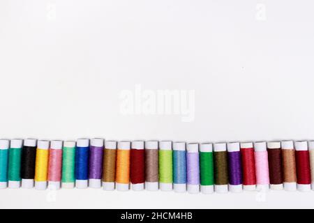 Satz mehrfarbiger Fadenumfänge auf weißem Hintergrund mit Textstelle. Näh- oder Schneiderei, für Werbung Stockfoto