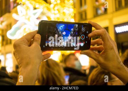 Frau mit Mobiltelefon, um Weihnachtslichter aufzunehmen, Malaga, Spanien. Stockfoto