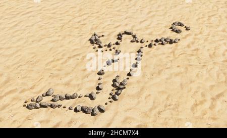 Konzept konzeptuelle Steine am Strand Sand handgemachte Symbolform, goldener sandiger Hintergrund, Volleyballspieler Schild. 3D Illustration Metapher für Sport Stockfoto