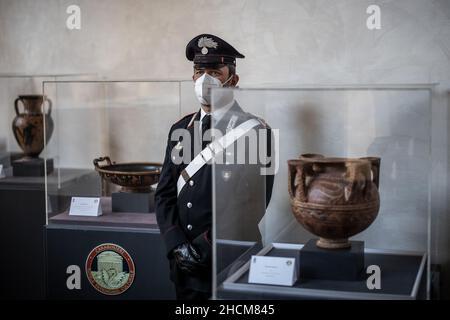 Rom, Italien. 30th Dez 2021. Ein Offizier der nationalen Gendarmerie Italiens, Carabinieri, steht neben Vasen, die während einer Pressekonferenz ausgestellt wurden. Die italienische Polizei hat rund 200 Kunstschätze im Wert von schätzungsweise zehn Millionen Euro (11,32 Millionen US-Dollar) geborgen. Quelle: Oliver Weiken/dpa/Alamy Live News Stockfoto