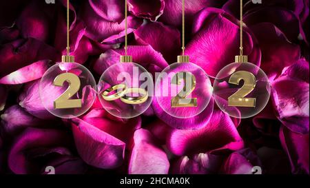 goldene Eheringe in durchsichtiger Glaskugel mit 2022 Ziffern und grungy violettem Rosenblatt Hintergrund Stockfoto