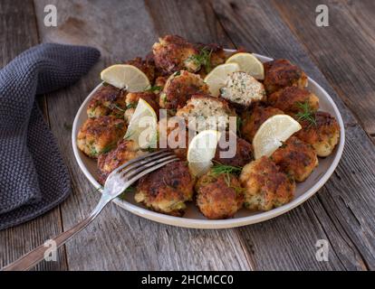 Hausgemachte frische, in der Pfanne gebratene Fischbällchen. Serviert auf einem Teller isoliert auf Holztisch Hintergrund. Stockfoto