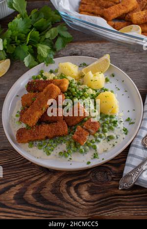 Fisch klebt mit Gemüse, Kartoffeln und Bechamelsauce auf einem Teller Stockfoto