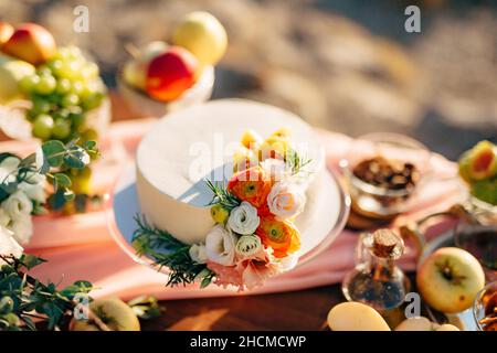 Hochzeitstorte mit Blumen geschmückt steht auf einem Tisch Stockfoto