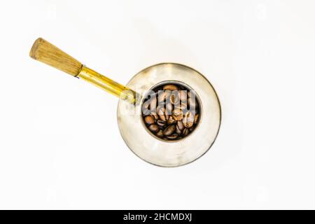 Frische italienische Kaffeebohnen in alten Vintage silbernen Kaffeekocher mit goldenem Griff isoliert auf weißem Hintergrund. Stockfoto