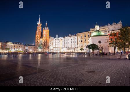 Hauptmarktplatz bei Nacht mit der Marienbasilika und der Kirche St. Wojciech - Krakau, Polen Stockfoto