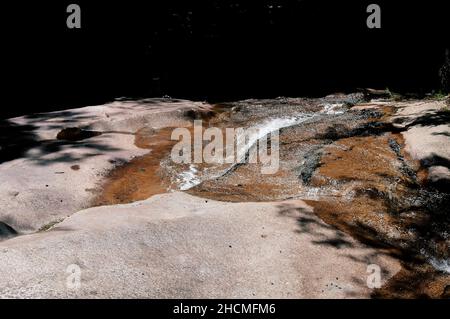 Tafelgestein an der Spitze der Flume-Schlucht, über die an einem sonnigen Tag in Lincoln New hampshire Wasser fließt. Stockfoto