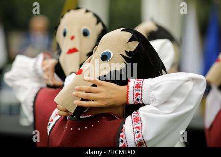 Braila, Rumänien - 26. August 2021: Frauen, die in traditionellen rumänischen Kostümen und mit rituellen Doppelgesichtsmasken gekleidet sind, führen einen traditionellen Tanz auf. Stockfoto