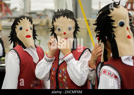 Braila, Rumänien - 26. August 2021: Frauen, die in traditionellen rumänischen Kostümen und mit rituellen Doppelgesichtsmasken gekleidet sind, führen einen traditionellen Tanz auf. Stockfoto