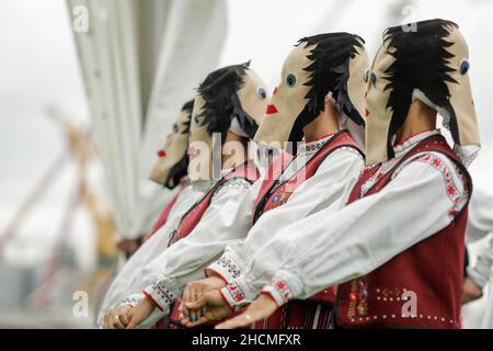 Braila, Rumänien - 26. August 2021: Frauen, die in traditionellen rumänischen Kostümen und mit rituellen Doppelgesichtsmasken gekleidet sind, führen einen traditionellen Tanz auf. Stockfoto